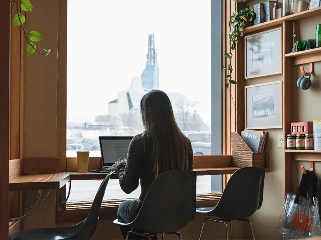 Woman working on laptop in front of window